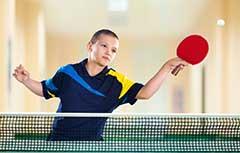 Young boy playing ping pong.